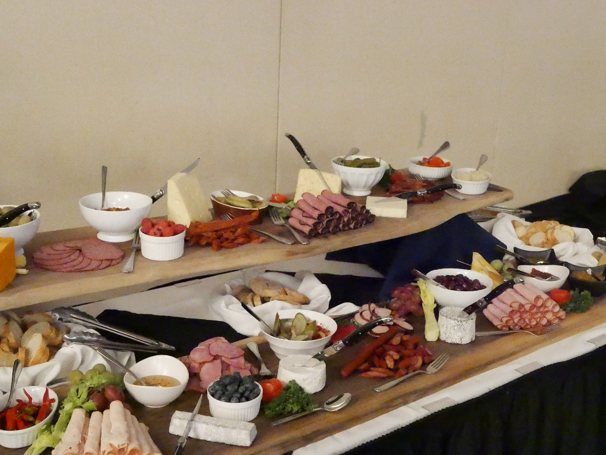 A table is filled with various charcuterie items like deli meats, cheeses and olives.